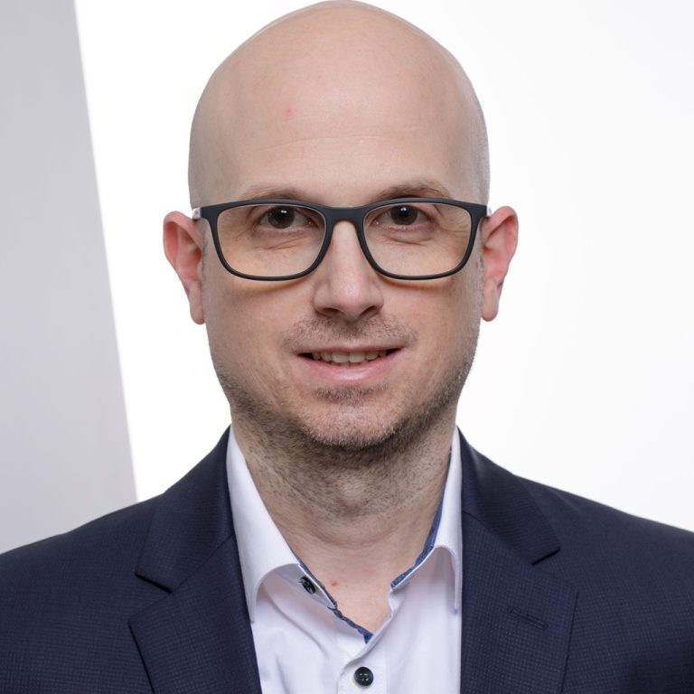 Portraitfoto von Daniel Radel mit blauem Anzug